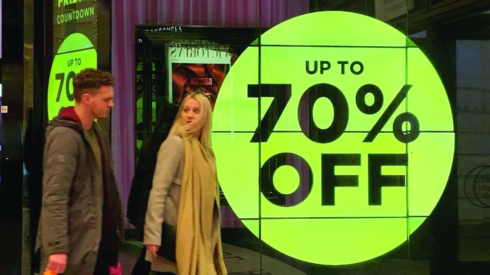 Shoppers walk past a retail store offering discounts  in central New York. — Reuters