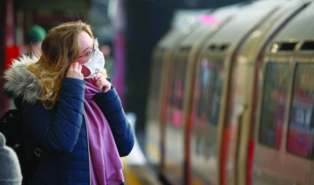 A woman adjusts her face mask at Barons Court Underground station in London. - AFP 