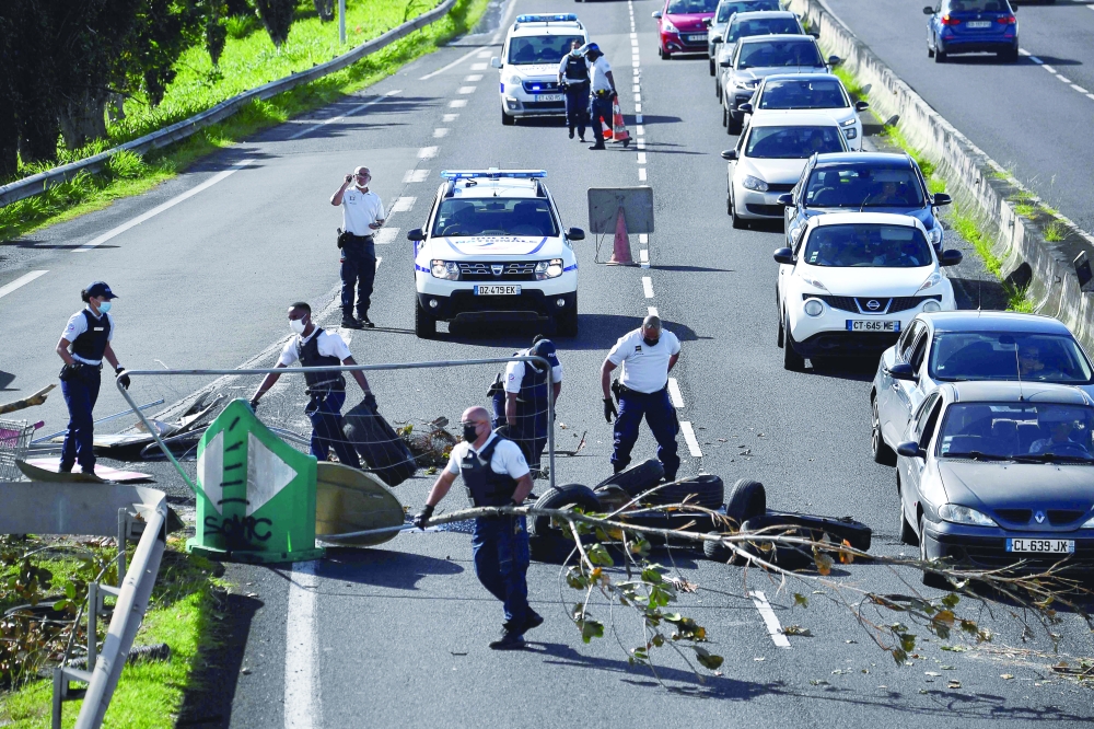 Police clear branches from a road  in Le Lamentin, on the French Caribbean island of Martinique after days of violent protests sparked by Covid-19 restrictions and social grievances. - AFP