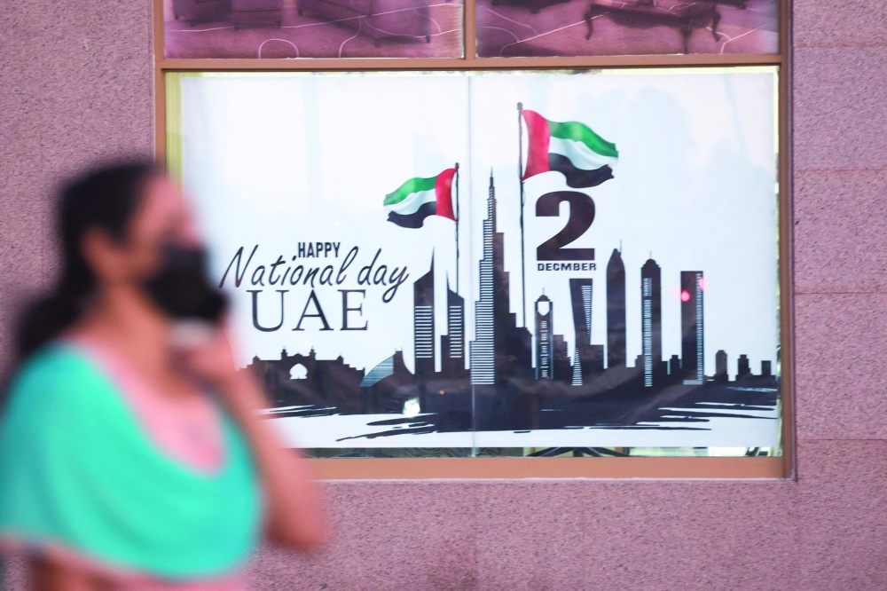 A woman walks past a poster celebrating the United Arab Emirates' 50th anniversary which falls on December 2 in Dubai. - AFP