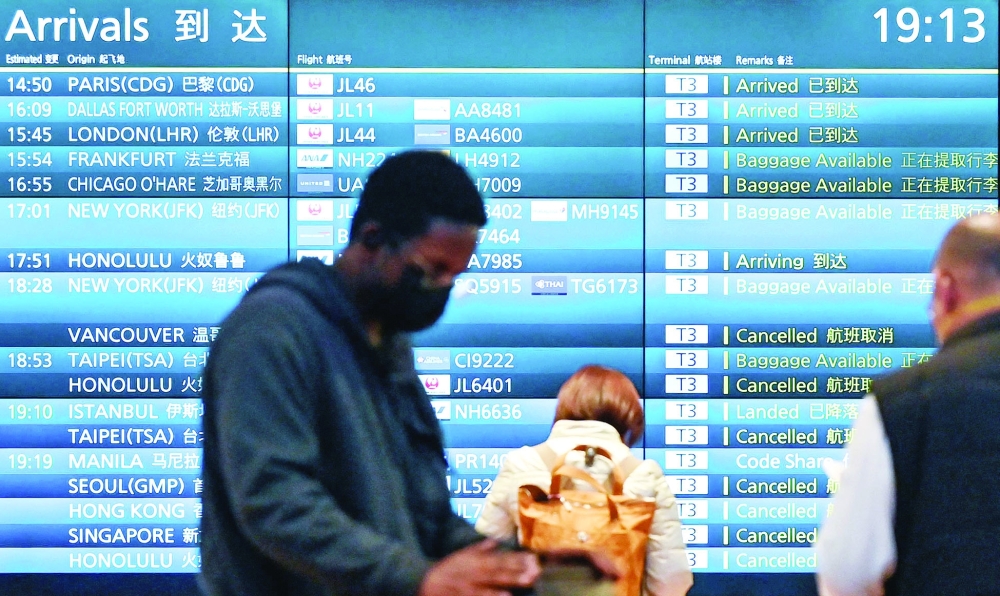 People stand in front of an arrivals board showing cancelled flights at Tokyo's Haneda international airport. - AFP

