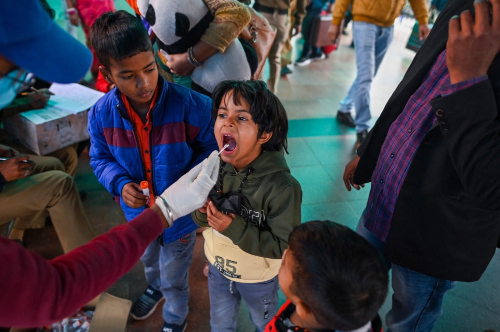 A health worker collects swab samples from a traveller to test for the Covid-19 coronavirus at a railway station in New Delhi on December 1, 2021. 