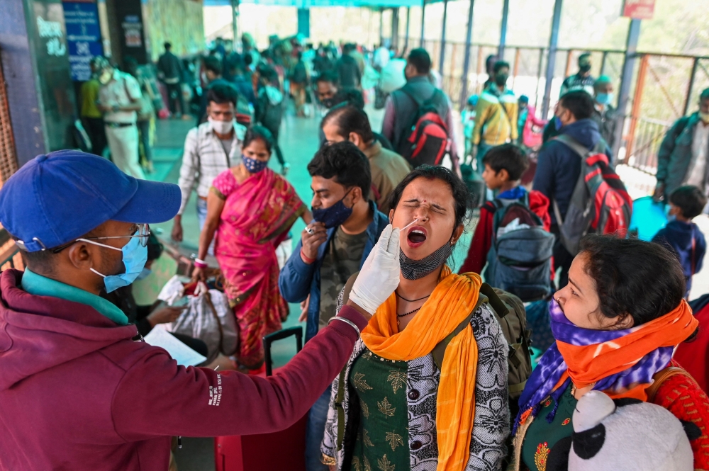 A health worker collects swab samples from a traveller to test for the Covid-19 coronavirus at a railway station in New Delhi on December 1, 2021.