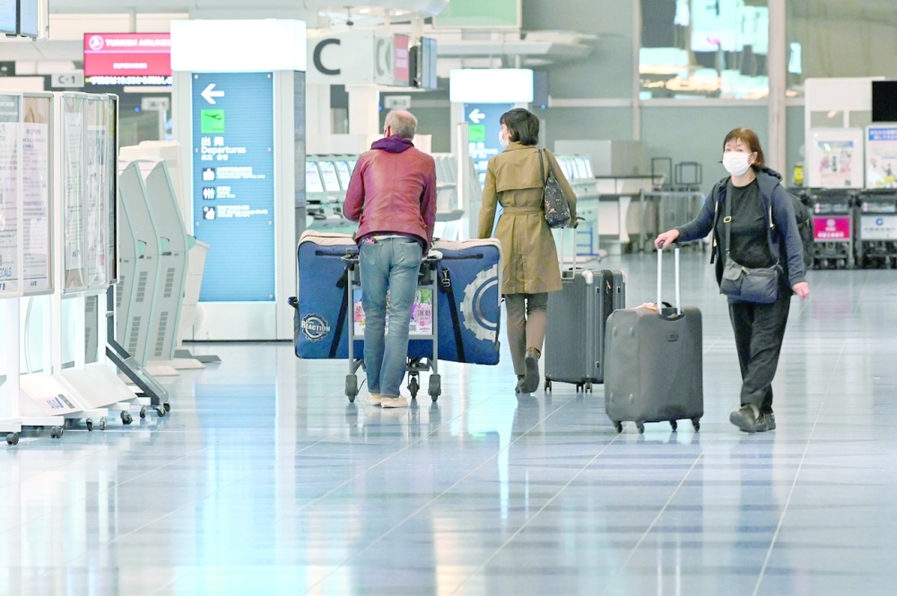 This picture taken on Wednesday shows travellers walking past check-in counters at an international flight departure floor at Tokyo's Haneda airport. - AFP