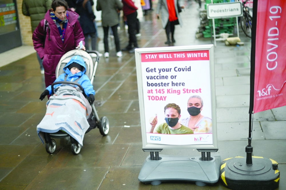 A woman walks past signage outside a pop-up vaccination centre for the Covid-19 vaccine or booster, in Hammersmith and Fulham in Greater London on Friday, as rollout accelerates in England. - AFP