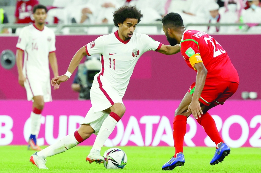 Oman's midfielder Harib al-Saadi (R) marks Qatar's midfielder Akram Afif during the FIFA Arab Cup match in Doha. -- AFP