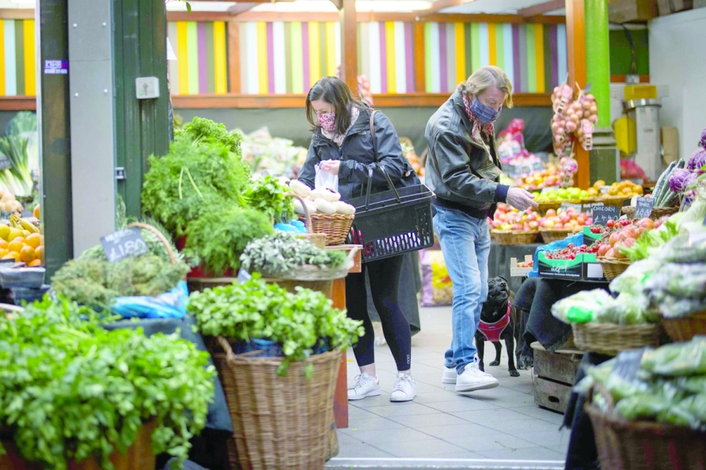 Customers wear face masks as they shop at a local market in London. — AFP
