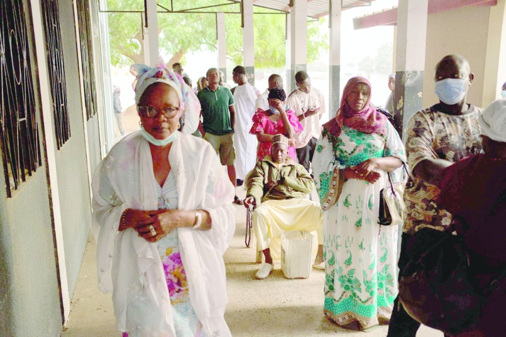 People wait in line ahead of the opening of a voting station in a market in the Kanifing neighbourhood in Banjul. - AFP