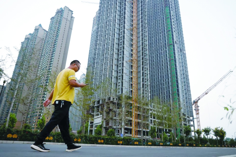 A man walks in front of unfinished residential buildings at the Evergrande Oasis, a housing complex developed by Evergrande Group, in Luoyang, China. — Reuters