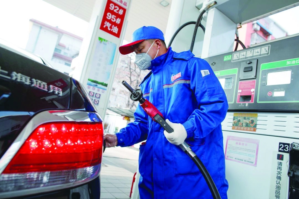 A pump attendant wears a mask as he refuels a car at a Sinopec gas station in Beijing, China. — Reuters