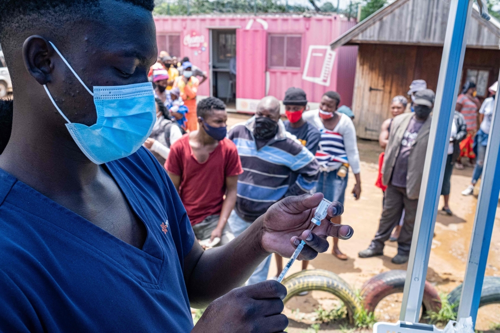 A health worker fills up a syringe with a vaccines dose against COVID-19 as people queue at the Kya Sands informal settlement to be vaccinated by the Witkoppen clinic in Johannesburg on December 8, 2021. Anti-Covid vaccines may lose effectiveness against Omicron, but one more dose could remedy this. Initial elements, notably given by the Pfizer laboratory, shed light on the capacity of the new variant to resist vaccination. Omicron is "probably not sufficiently neutralized after two doses", admitted Wednesday the groups Pfizer and BioNTech, whose anti-Covid vaccine is given in two injections. (Photo by EMMANUEL CROSET / AFP)

