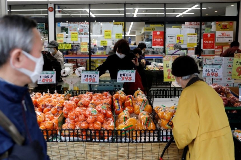 Shoppers buy food at a supermarket in Tokyo. — Reuters