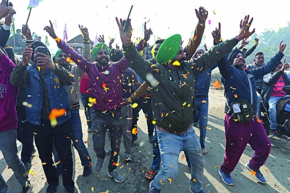 Farmers cheer as they prepare to leave the protest site at the Delhi-Haryana state border in Singhu on Saturday. - AFP

