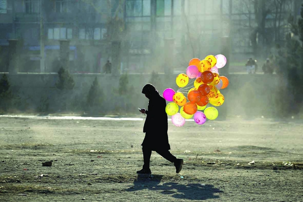 An Afghan hawker selling balloons walks along a path in a ground in Chaman-e-Hozori area in Kabul. - AFP
