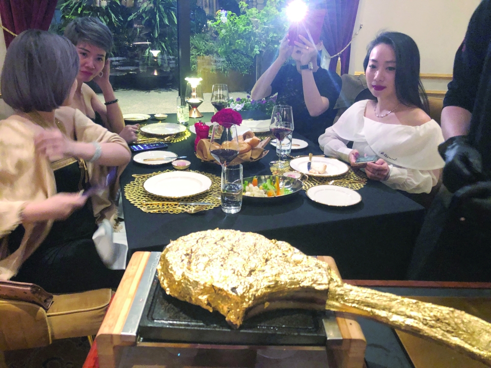 A customer takes pictures of a gold leaf-coated steak, at a Dolce By Wyndham Hanoi Golden Lake hotel, in Hanoi
