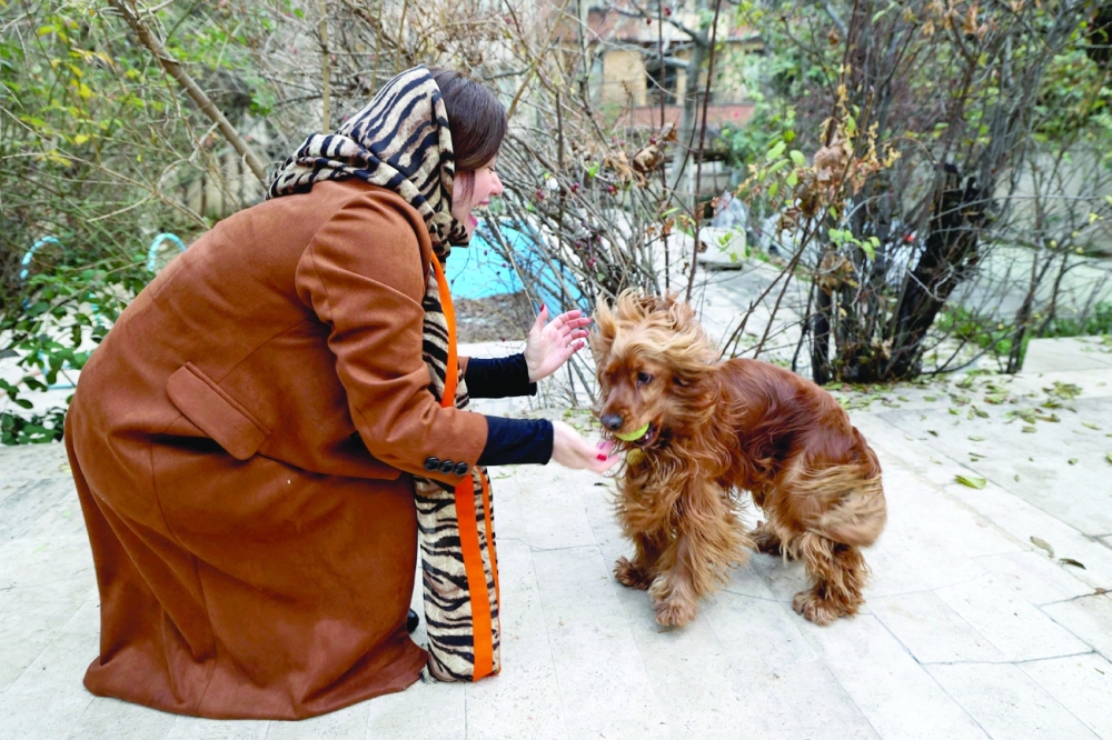 An Iranian woman plays with her dog in a yard near her house in northern Tehran. -- AFP