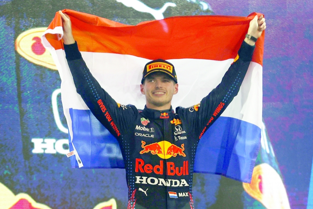 Red Bull's Max Verstappen celebrates winning the race and the world championship with the Netherlands flag on the podium. -- Reuters