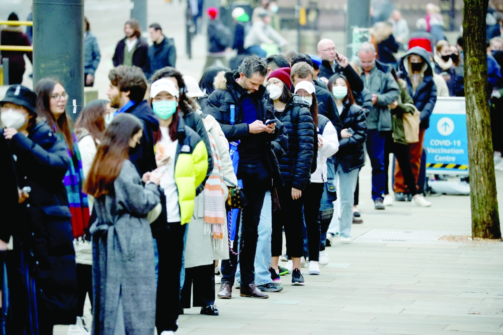 People queue to receive Covid-19 vaccine and booster doses, as the spread of Covid-19 continues, at a vaccination centre in Manchester, Britain, on Tuesday. - Reuters