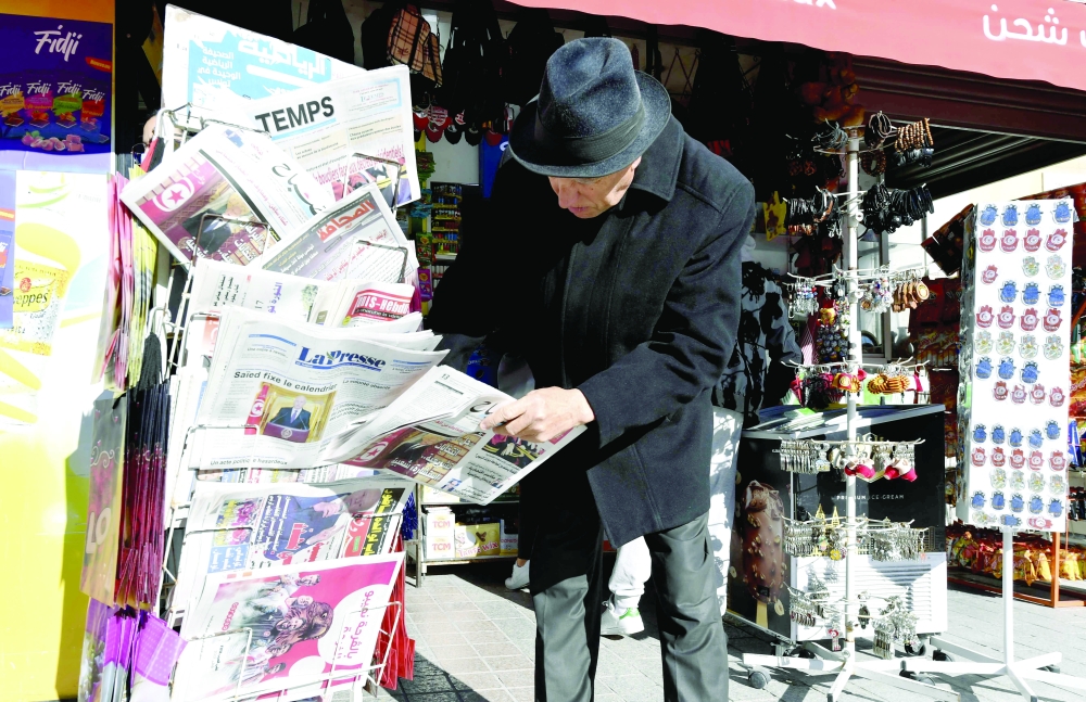 A Tunisian man checks newspapers on a stand on Habib Bourguiba Avenue in Tunis on Tuesday, one day after Tunisia's president extended his months-long suspension of parliament. - AFP