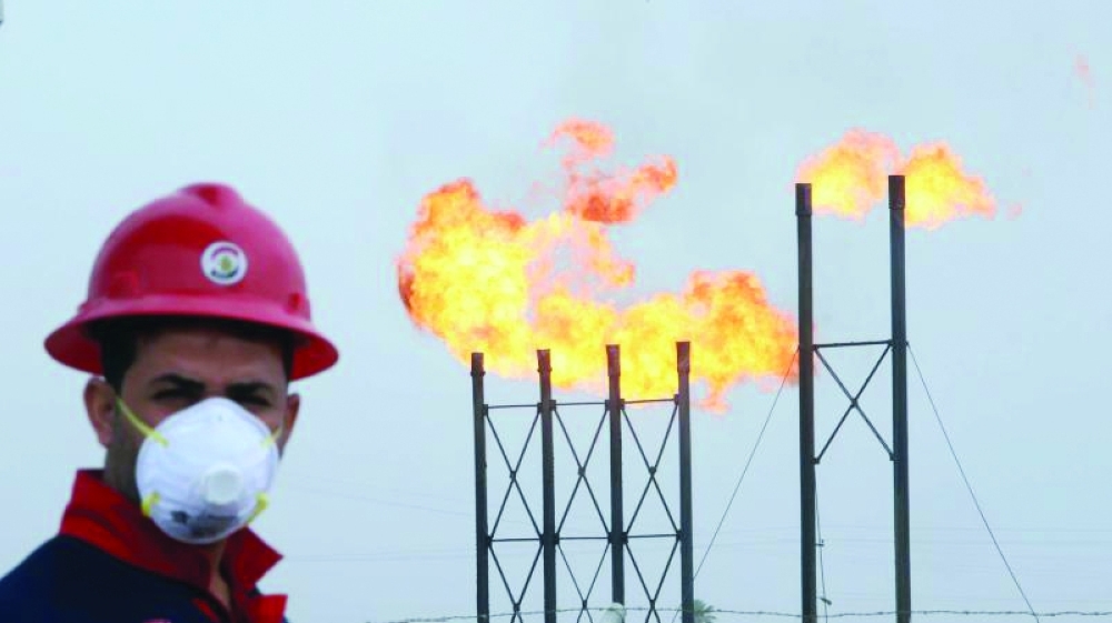 Flames emerge from flare stacks at Nahr Bin Umar oilfield as a worker wears a mask in Basra, Iraq. — Reuters