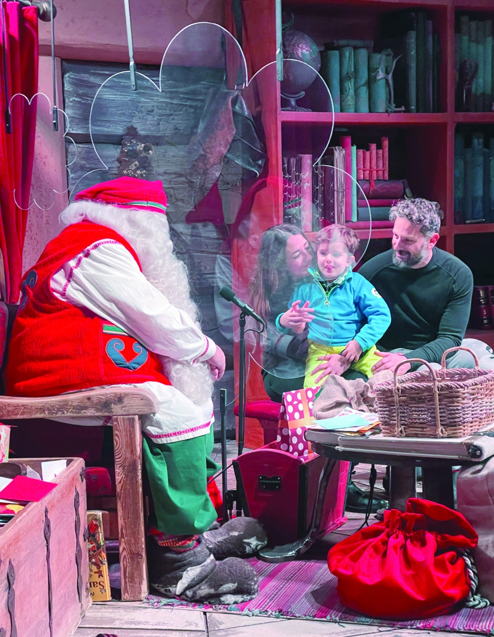 A man dressed as Santa Claus talks to visitors behind a plexiglass screen in his chamber at the Santa Claus Village in the Arctic Circle near Rovaniemi, Finland. — Reuters