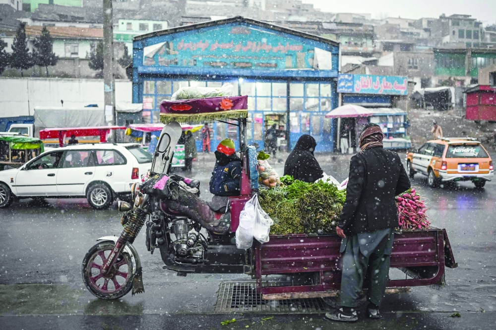 A vendor sells vegetables along a road during the first snow in Kabul on Wednesday. -- AFP
