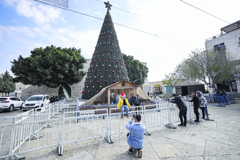 A child poses for a picture before the giant Christmas tree in the almost empty Manger Square outside the Church of the Nativity, traditionally believed to be the birthplace of Christ, in the biblical West Bank city of Bethlehem on Wednesday. — AFP