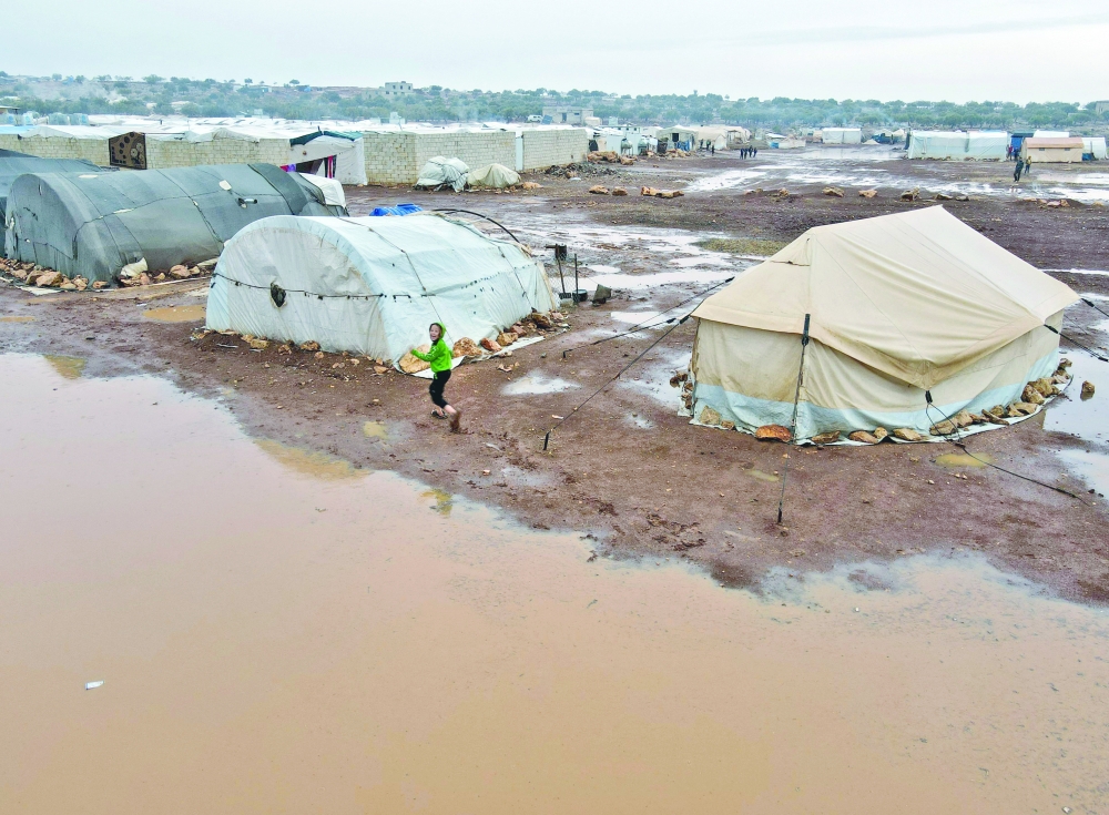 An aerial picture taken by a drone shows a child running at a camp for Syrians displaced by conflict that was flooded during heavy rains near the village of Kafr Uruq, in Syria's Idlib province. — AFP