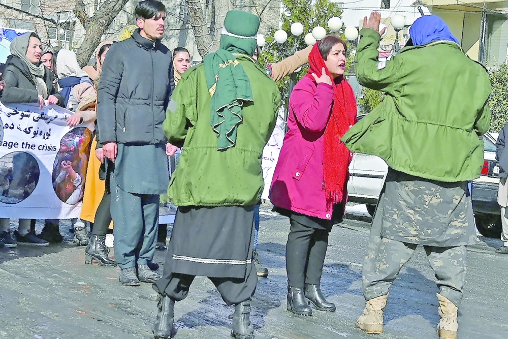 An Afghan woman protester speaks with Taliban fighters during a demonstration in Kabul. -- AFP