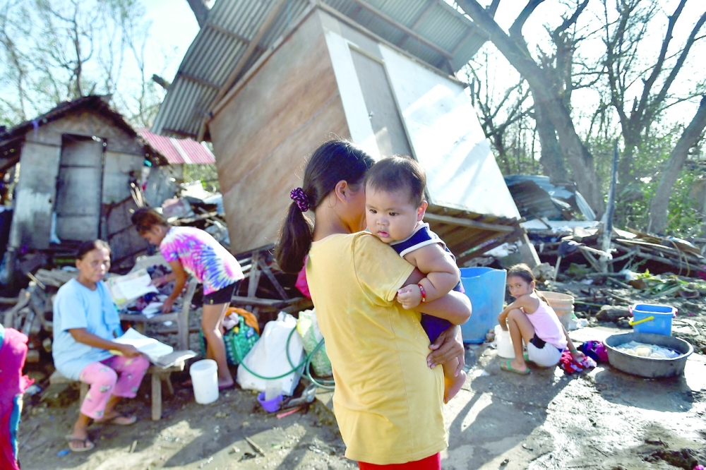 Residents gather next to their destroyed house in Carcar, Philippines' Cebu province on Saturday days after Super Typhoon Rai hit the city. — AFP