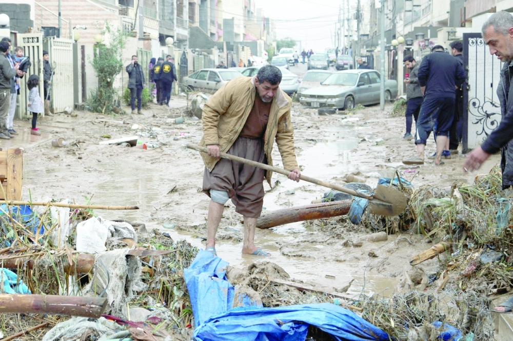 Residents clean a road full of mud after heavy rainfall in Erbil on Friday. — Reuters