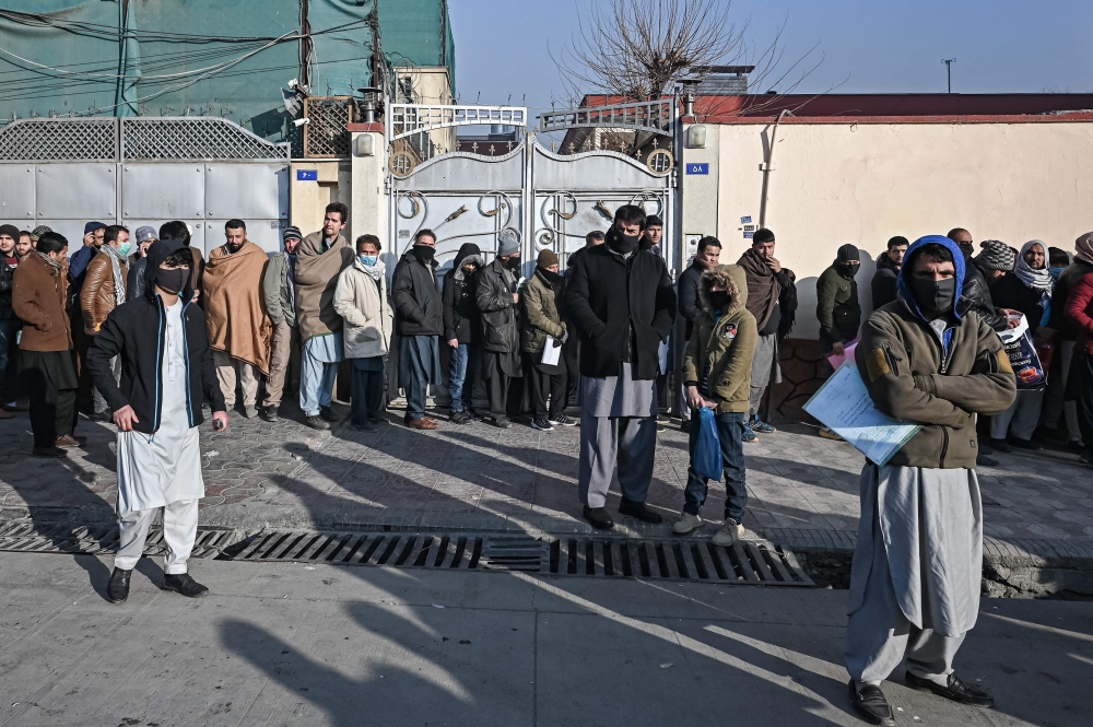 People queue to enter the passport office at a checkpoint in Kabul on December 19, 2021, after Afghanistan's Taliban authorities said they will resume issuing passports
