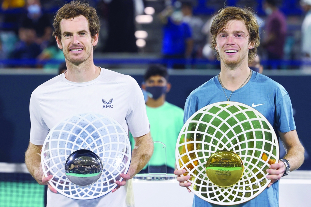 (R to L) First-place winner Andrey Rublev of Russia holds up his trophy alongside second-place winner Andy Murray of Britain during the awards ceremony after the final match of the Mubadala World Tennis Championship. -- AFP