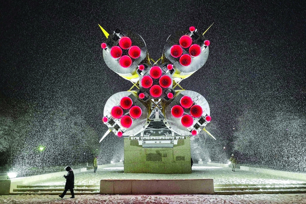 A woman walks under snowfall in front of a Soyuz rocket installed as a monument in Baikonur city, near the Russian leased Kazakh Baikonur cosmodrome. After a decade-long hiatus, Russia is relaunching an ambitious bid for dominion over the world's budding space tourism industry, jostling with zealous billionaires, the United States, and rising China. — AFP