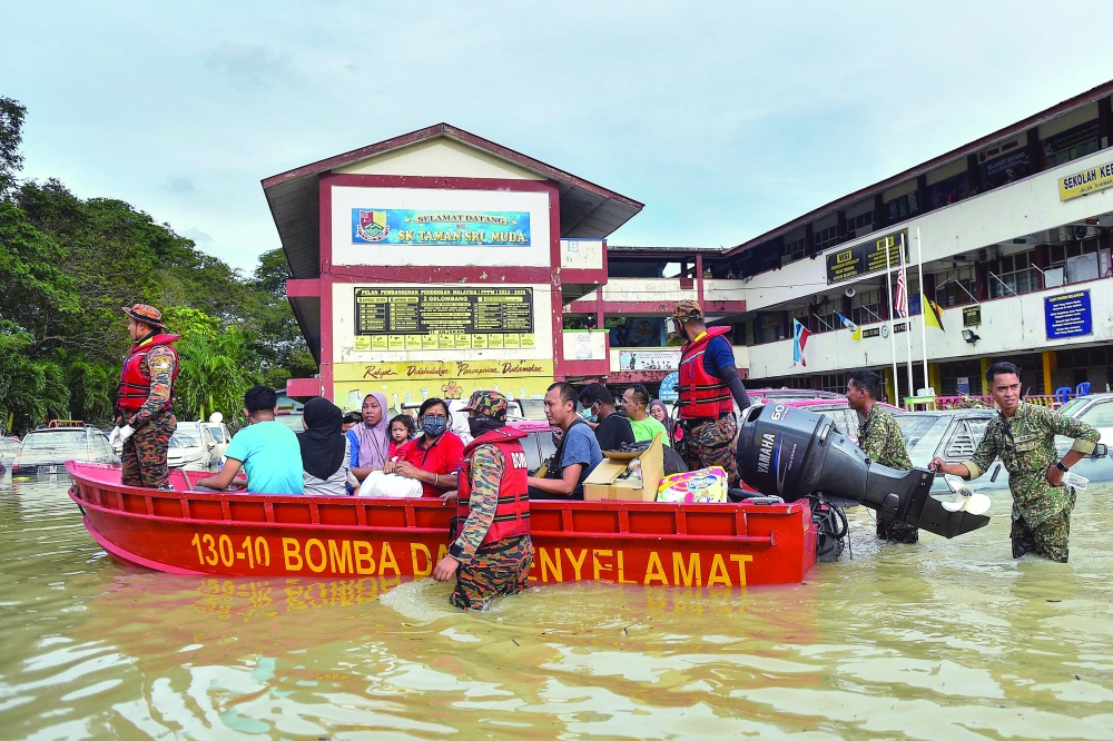 Rescue officials evacuate people in a boat in Shah Alam, Selangor, as Malaysia faces some of its worst floods for years. -- AFP
