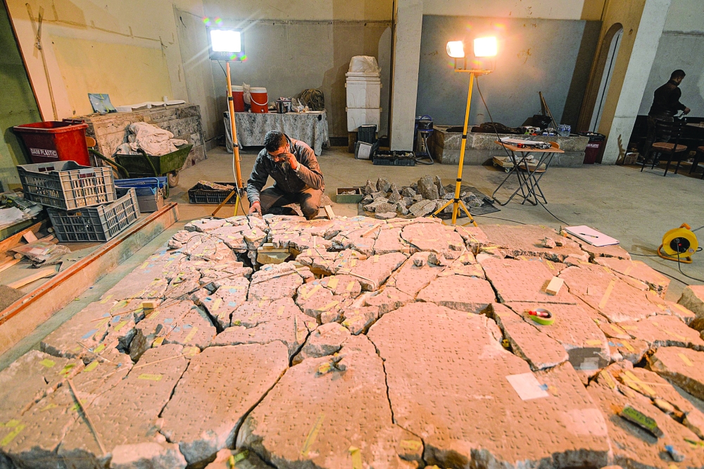 A worker at the Mosul Museum tries to reassemble from broken fragments a larger artefact bearing cuneiform inscriptions, at the museum in Iraq's northern city on December 14. - AFP 