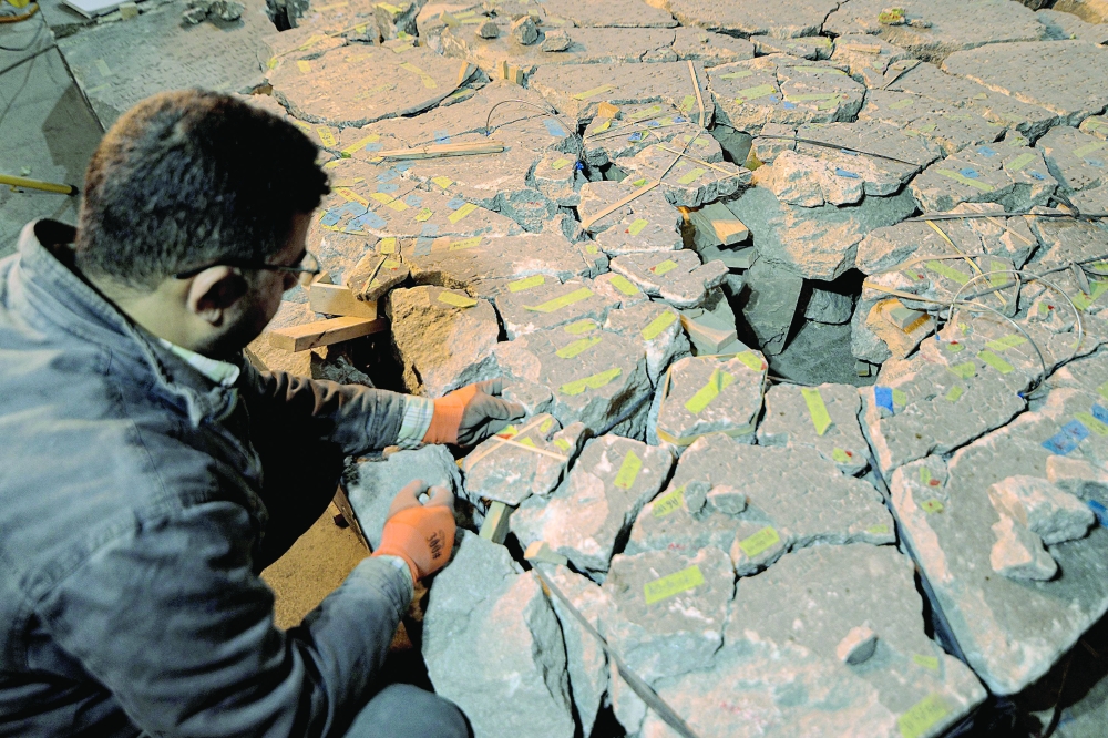A worker at the Mosul Museum tries to reassemble from broken fragments a larger artefact bearing cuneiform inscriptions, at the museum in Iraq's northern city on December 14. - AFP 