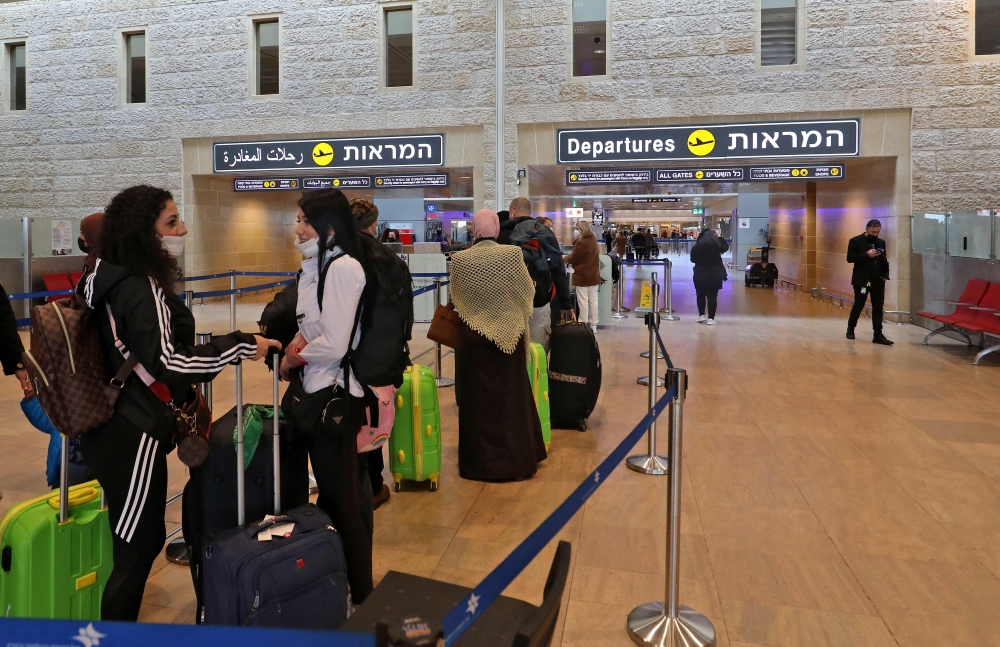 Travellers queue with their luggage at the check-in counter ahead of their departing flights at Israel's Ben Gurion Airport in Lod, east of Tel Aviv, on December 21, 2021.  