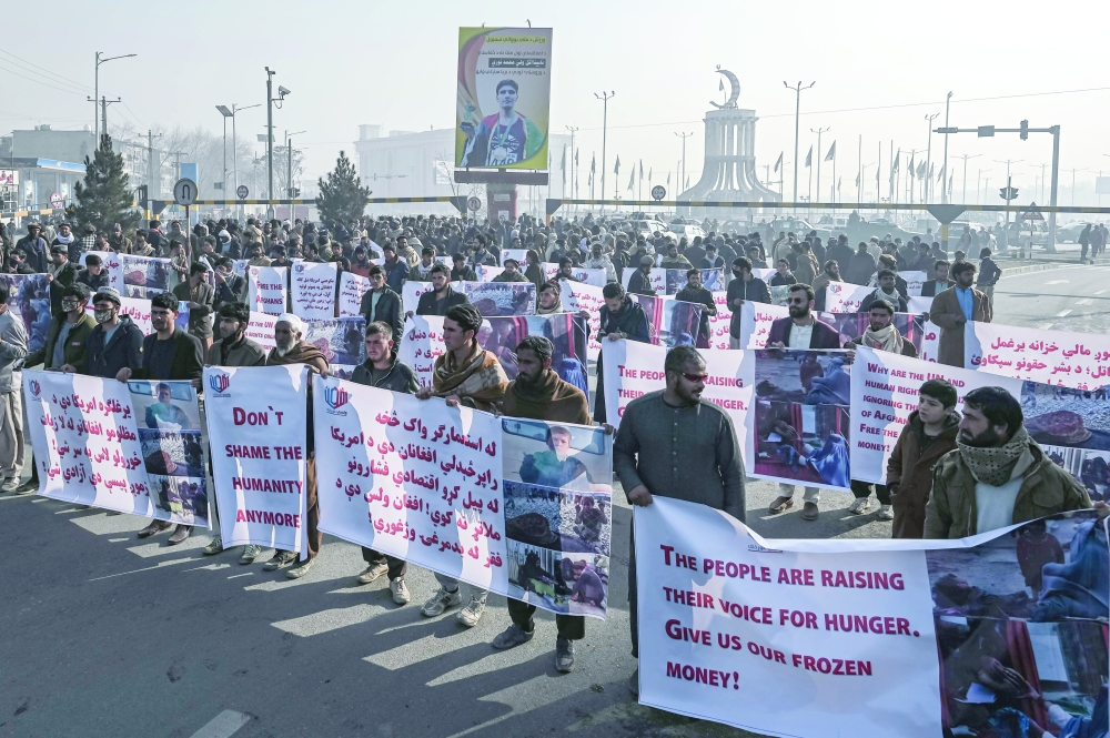 People hold banners before marching on the street during a protest in Kabul on Tuesday, as the country struggles with a deep economic crisis. -  AFP
