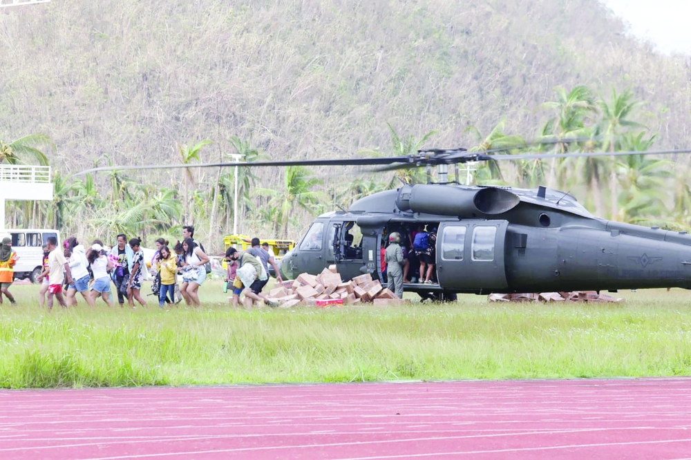 Residents, who were not able to take a flight out with a Philippine air force blackhawk helicopter which transported relief goods, leave the landing site at a sports complex in Dapa town, Siargao island on Tuesday. - AFP