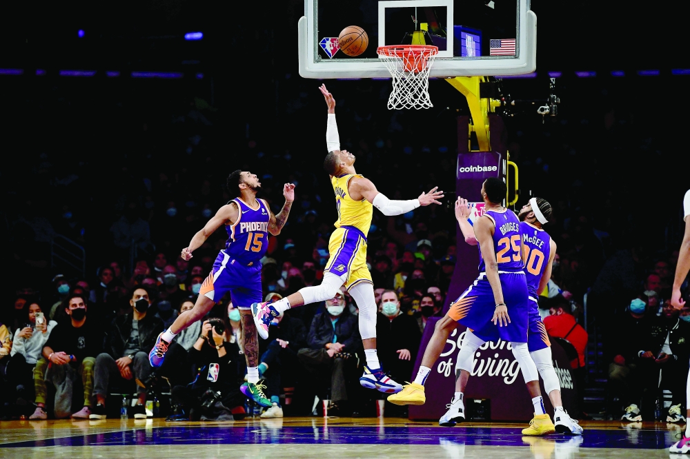 Dec 21, 2021; Los Angeles, California, USA; Los Angeles Lakers guard Russell Westbrook (0) shoots against Phoenix Suns guard Cameron Payne (15) center JaVale McGee (00) and forward Mikal Bridges (25) during the second half at Staples Center. Mandatory Credit: Gary A. Vasquez-USA TODAY Sports
