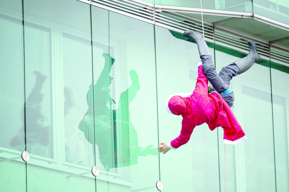 A climber disguised as Santa Claus goes down a paediatric clinic building in Ljubljana, Slovenia, on Thursday. - AFP

