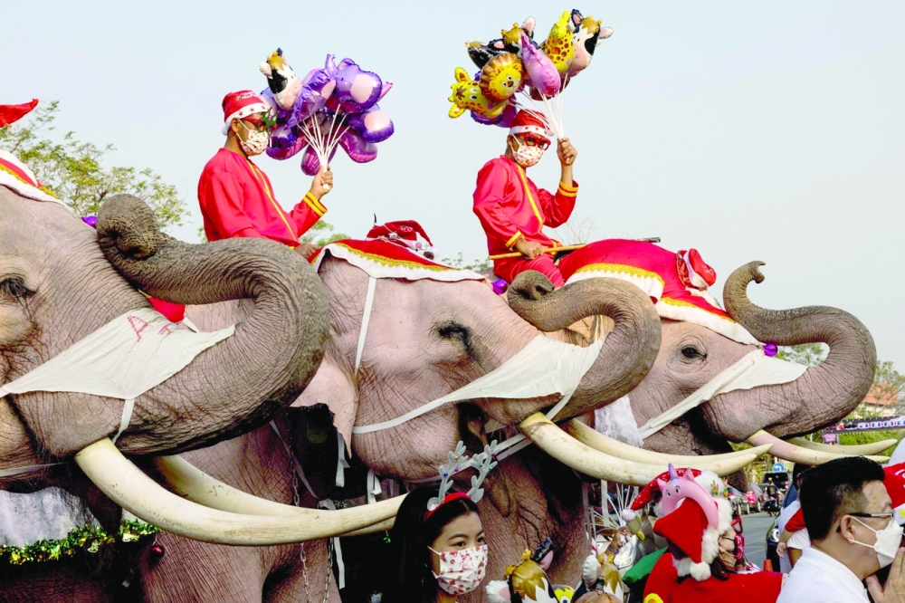 Mahouts and their elephants pose for children during Christmas celebrations at the Jirasart Witthaya school in Ayutthaya on Friday. - AFP