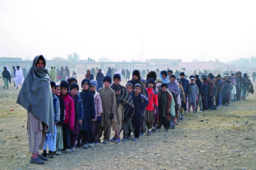 Students from a madrasa stand in a queue before offering special prayers for rains along with others at Eidgah in Kandahar on Saturday. -- AFP
