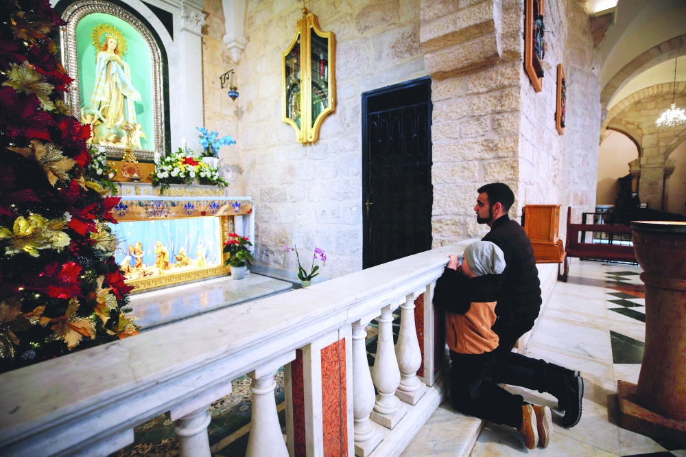 Worshipers pray ahead of Christmas morning mass at Saint Catherine's Church, in the Church of the Nativity, in Bethlehem on Saturday. — Reuters