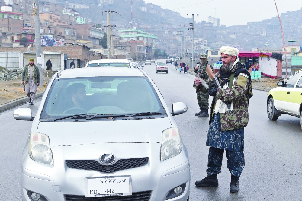 A Taliban fighter checks the document of a motorist at a checkpoint in Kabul. -- AFP

