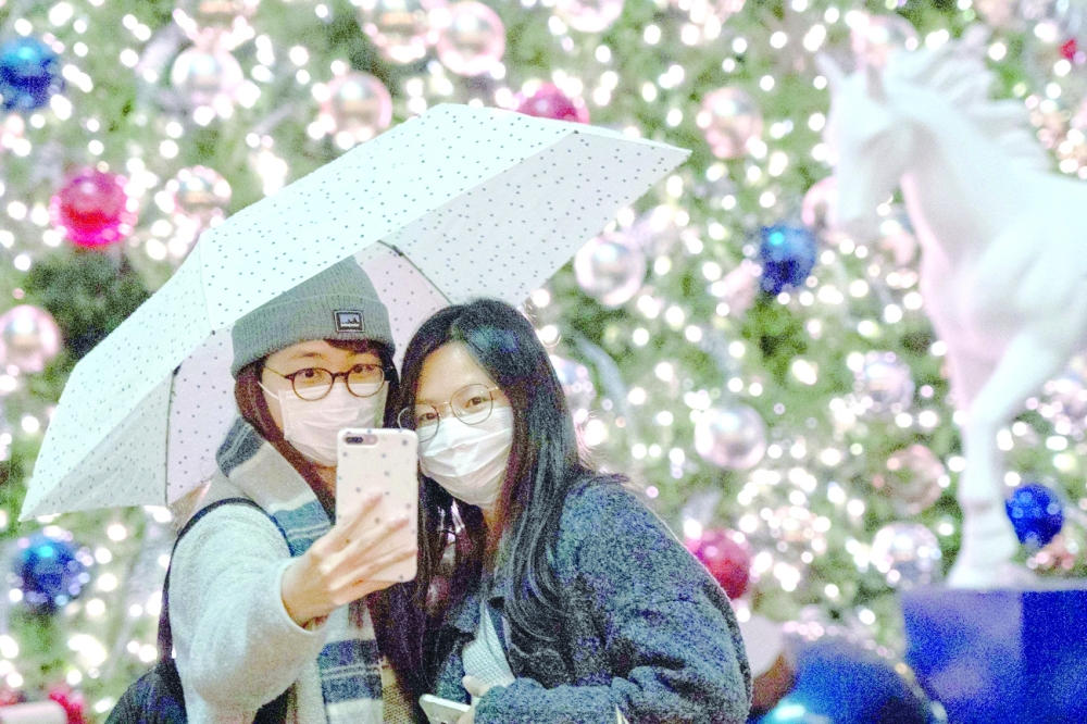 People pose for a selfie in front of a Christmas Tree during Boxing Day at Tai Kwun in Hong Kong Central district on Sunday. -- AFP