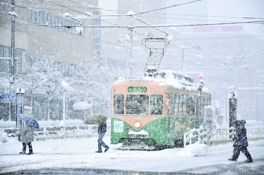 People cross a street in heavy snow in the city of Toyama. -- AFP
