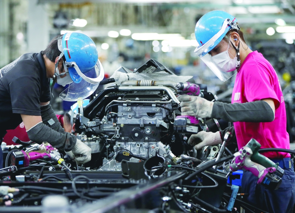 Employees work on the automobile assembly line at the factory of Mitsubishi Fuso Truck and Bus Corp. in Kawasaki. — Reuters