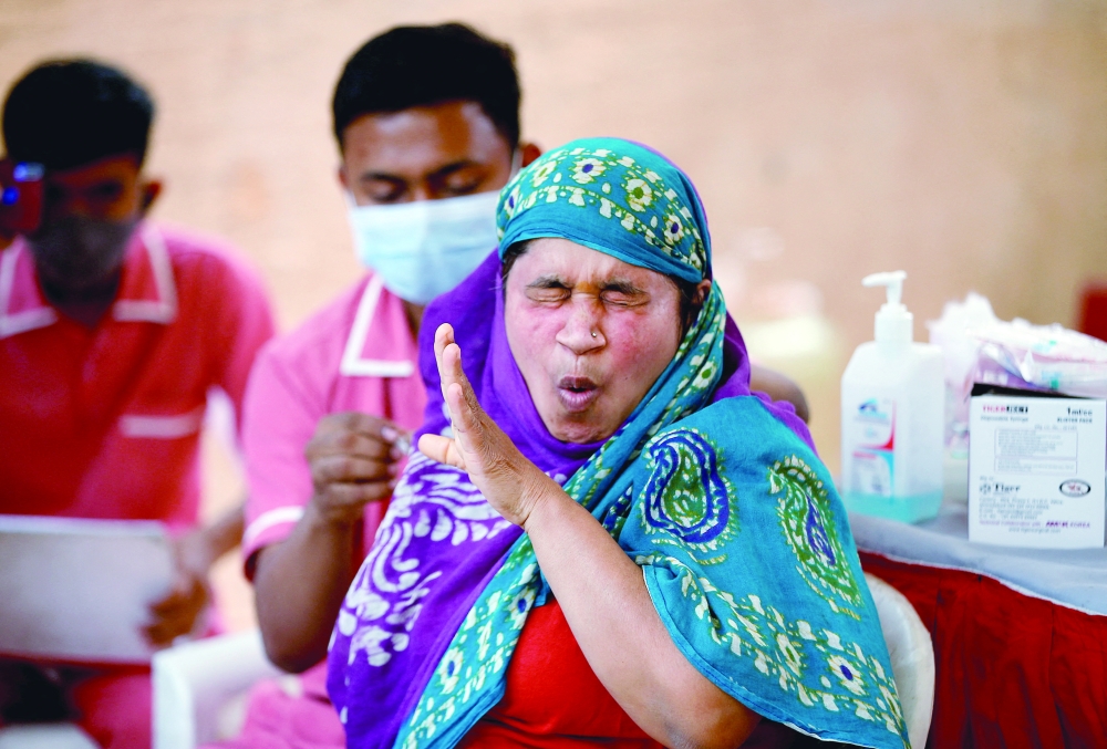 A woman reacts as she receives a dose of the Covishield vaccine against Covid-19, manufactured by Serum Institute of India, at a vaccination centre in Ahmedabad, on Tuesday. - Reuters